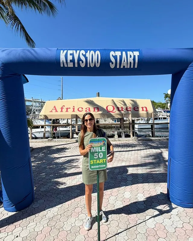 La víspera: Mónica bajo el arco de salida del Keys 100, con el letrero “Mile 50 Start”.