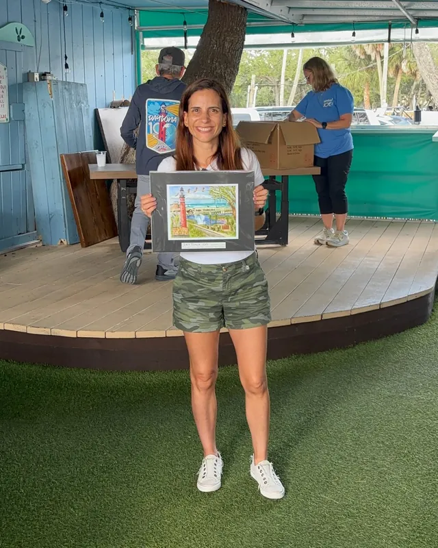 Mónica sostiene su premio de la categoría Masters, un cuadro del faro, en la premiación del Daytona 100.